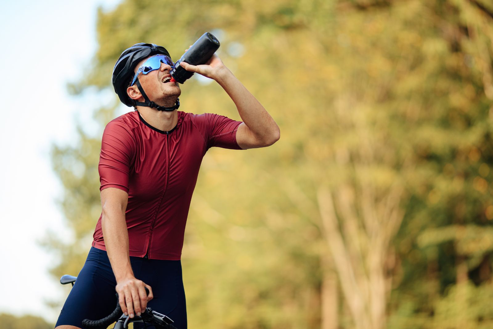 Jak zamontować uchwyt na bidon do roweru - rowerzysta pije wodę z bidonu